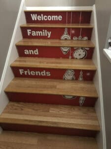 Wooden stairs decorated with red panels featuring white text—"Welcome Family and Friends"—plus charming Christmas ornaments and holiday designs, bring festive cheer much like creative vehicle wraps Spring Grove businesses proudly display.