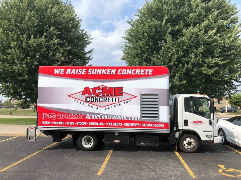 A white truck with "ACME Concrete Raising & Repair Inc" and "We Raise Sunken Concrete" on the side, parked in a lot. Services and contact info are listed in red and white, with trees in the background.